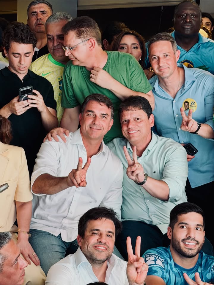 Flávio Bolsonaro e aliados sorriem e fazem o V durante a apuração